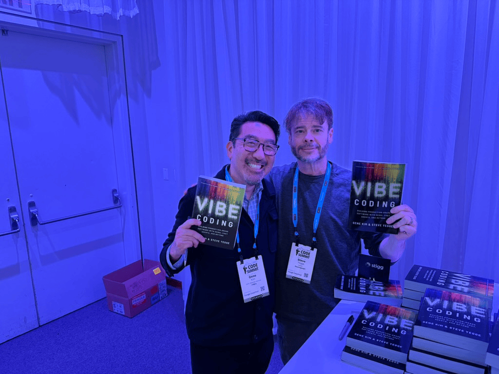 Steve Yegge and Gene Kim holding copies of Vibe Coding at a book signing