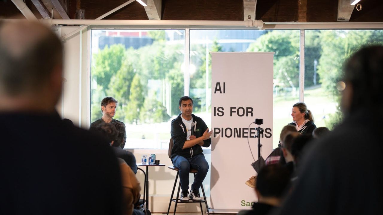 Steve Yegge, Ajit Banerjee, and Milkana Brace on the panel at AI House Seattle, in front of an 'AI is for Pioneers' banner